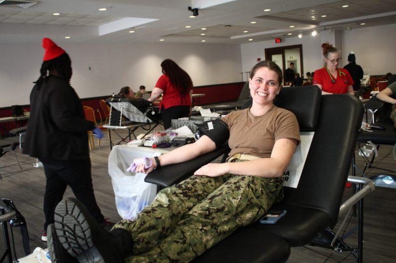 一名身着制服的学生在等待献血时对着镜头微笑. 
